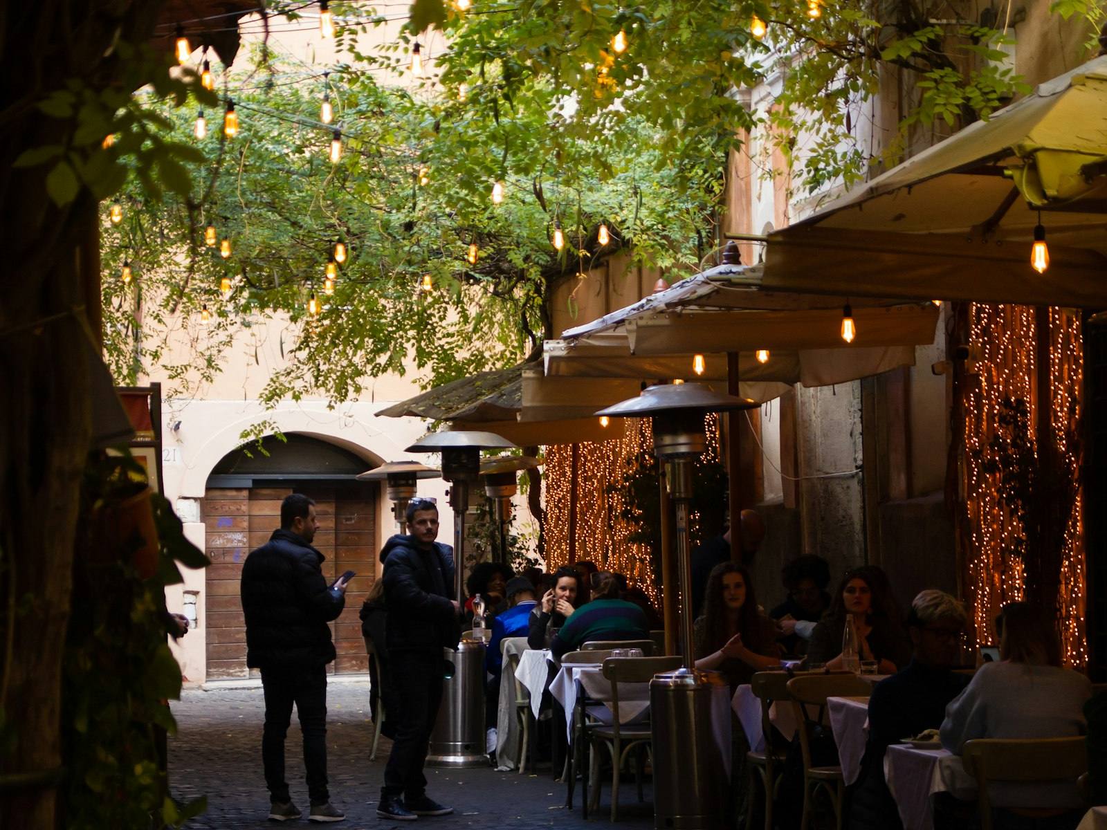 Callejuela napolitana con mesas al aire libre y luces cálidas